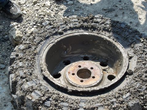 1996 Ford Bronco - Close-up of a muddy tire and rim, likely from an off-road vehicle, with visible lug nut holes.