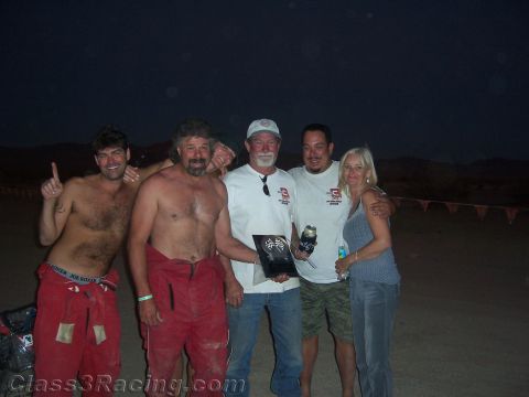 1990 Ford Bronco - Five people pose together at night in the desert, with two shirtless men and others holding an award plaque and drinks.