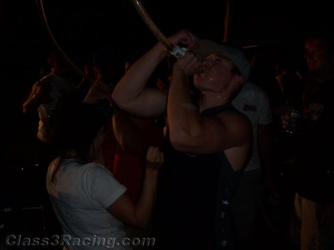 1990 Ford Bronco - dark nighttime photo of a man tilting his head back to drink from a hose held overhead while a woman holds his arm.