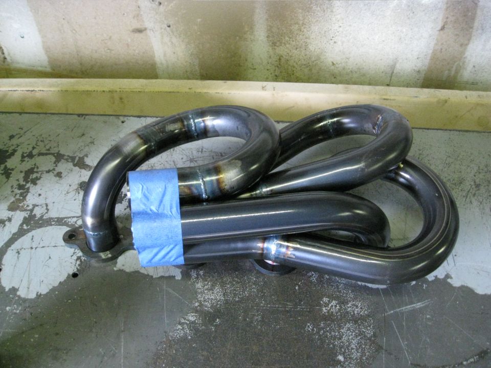 Exhaust manifold with blue tape on pipes, welded seams visible