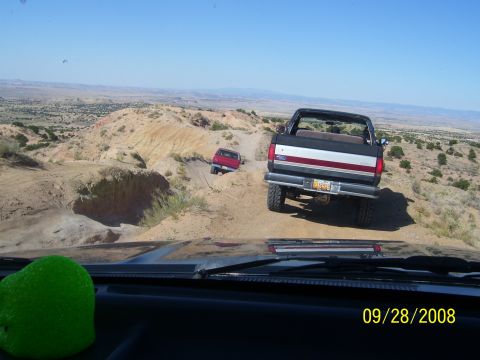 1993 Ford Bronco - Two vehicles navigate a dusty off-road trail in a desert landscape.