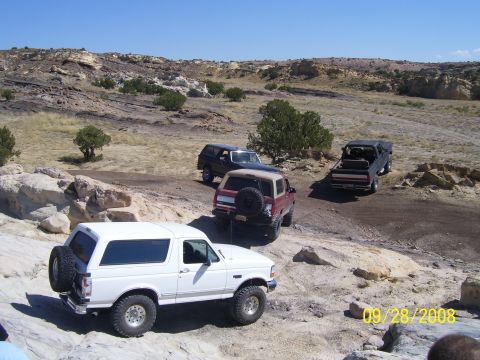 1993 Ford Bronco - A white 1993 Ford Bronco navigates rocky terrain alongside other off-road vehicles.