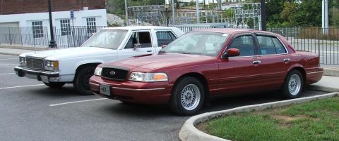 1985 Ford Crown Victoria LTD - A red Ford Crown Victoria is parked next to a white sedan in a parking lot.