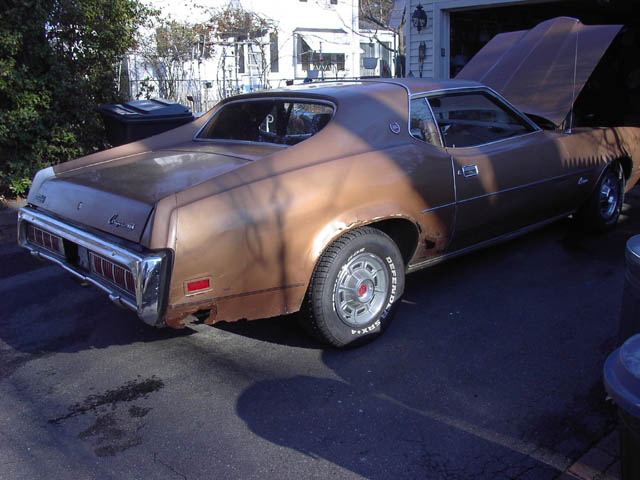 Brown 1973 Mercury Cougar coupe, rear three-quarter view in driveway with hood up, faded paint and rust
