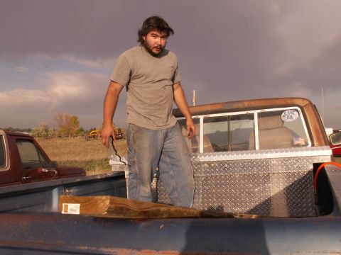 1977 Ford F-250 - Man standing in the bed of a 1977 Ford F-250 with a toolbox and another truck in the background.