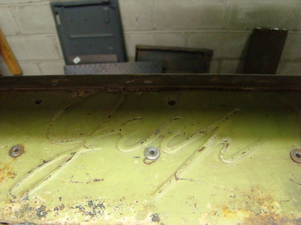 Close-up of embossed lettering on a green metal panel, possibly from a vehicle part