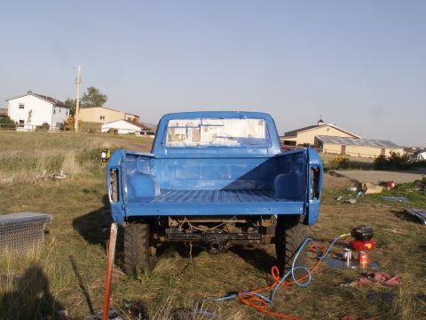 1977 Ford F-250 - A blue pickup truck is parked outdoors, showing its bed and rear end. The windows are taped, suggesting it's being prepped for painting.
