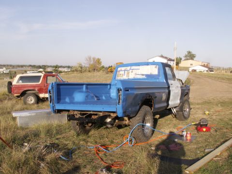1977 Ford F-250 - A blue 1977 Ford F-250 pickup truck is parked in a field with its hood open, alongside a red SUV.