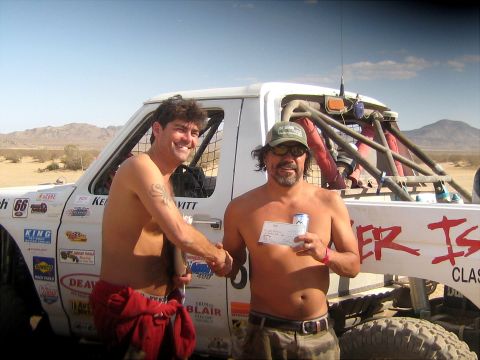 1996 Ford Bronco - Two men celebrate with a check next to a desert racing trophy truck.