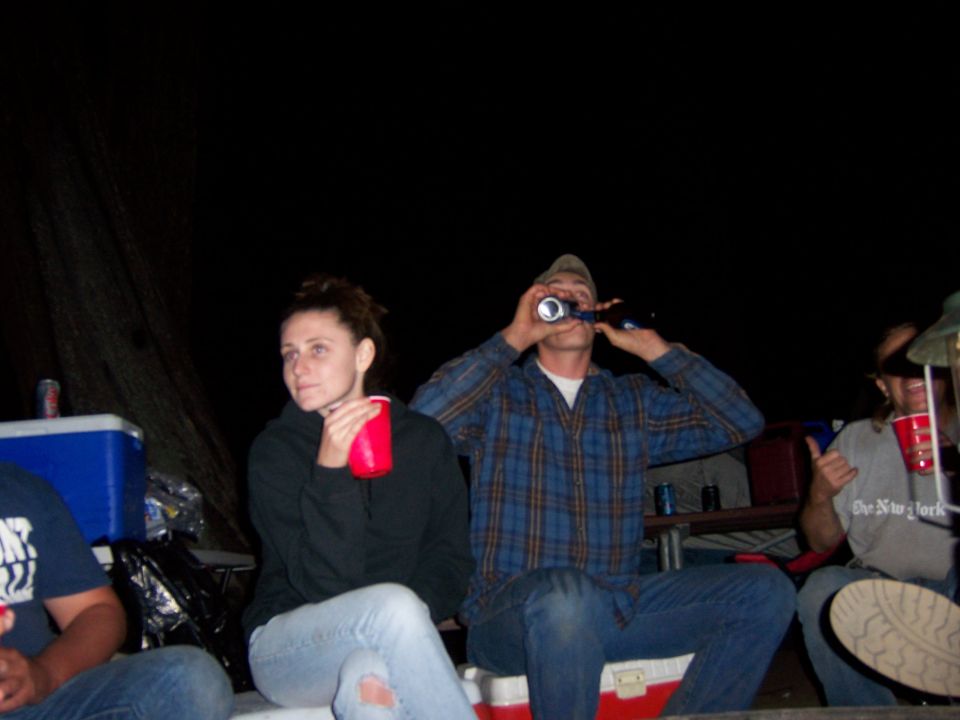 Group of people drinking at a campsite at night