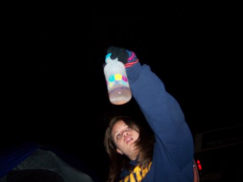 1991 Ford Bronco - Person holds up a water bottle at night, with a tent in the background.
