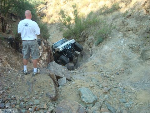 1986 Toyota Hilux - Modified 1986 Toyota Hilux tackles a challenging rocky obstacle on an off-road trail.