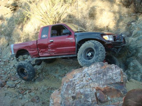 1986 Toyota Hilux - This modified Toyota Tacoma is navigating a difficult rocky terrain.