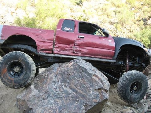 1986 Toyota Hilux - This heavily modified Toyota pickup is navigating a challenging rocky terrain.