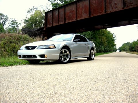 1998 Ford Taurus - A silver Ford Mustang is parked on a road beneath a railway bridge.