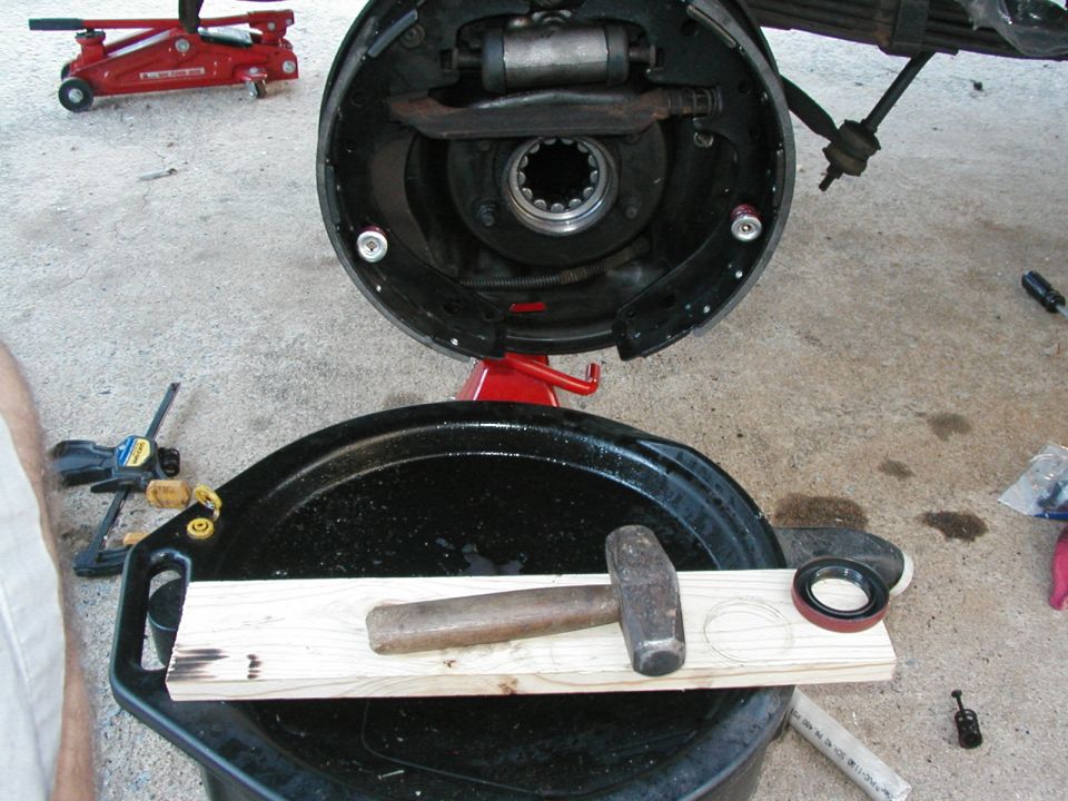 Once the backing plate is clean, put the new bearing and seal in.  I used my old bearing against the new one and 1x against the old bearing.  Gentle but firm, bang the bearing in.  You should feel a little raised line inside the axle shaft which the bearing stops at.  Used the wood against the new seal and beat that in also (careful with that one, the bearing can take a little more abuse).  Photo also shows new brakes in place.  Reused the two parking brake bars, everything else is new.