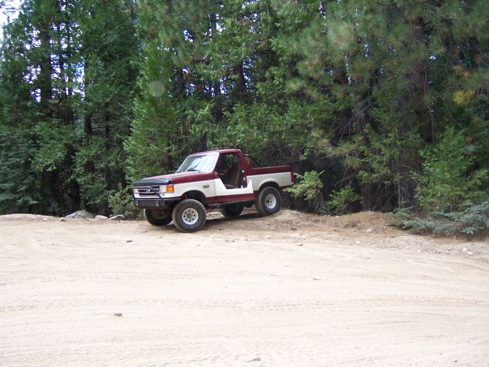 1991 Ford Bronco parked on a dirt road with trees in the background
