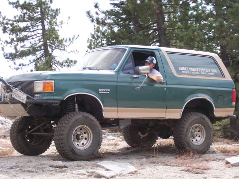1991 Ford Bronco - A modified 1991 Ford Bronco is shown off-road with a driver behind the wheel.