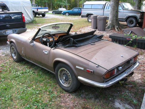 1991 Ford Bronco - A brown Triumph Spitfire convertible sits in a grassy area with several trucks visible in the background.