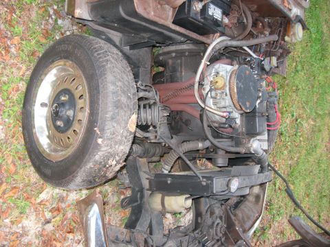1991 Ford Bronco - Close-up view of a car's engine compartment, showing mechanical components and a front tire.