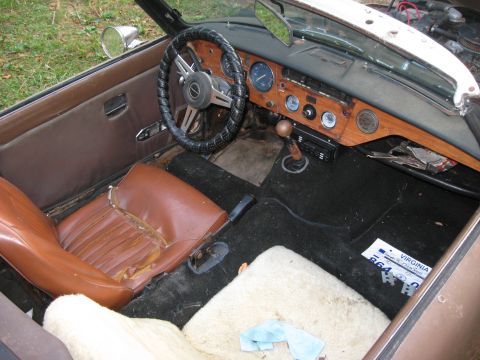1991 Ford Bronco - The interior of a vintage convertible shows worn seats and a wooden dashboard with multiple gauges.
