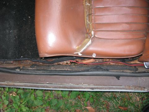 1991 Ford Bronco - The interior of a vehicle shows a damaged seat and a rusty door sill with exposed wiring.