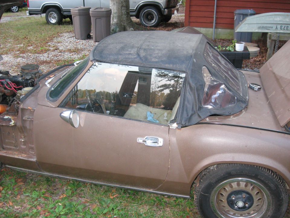 Side view of a brown convertible with a black soft top and clear plastic rear windows
