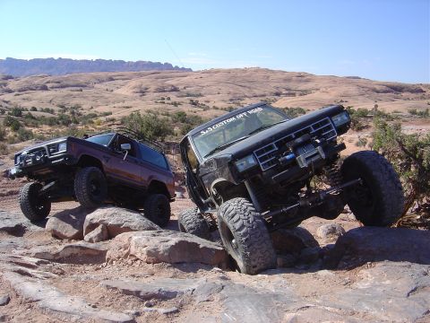 1986 Ford Bronco II - Two modified Ford Bronco II SUVs navigate a challenging rocky trail in Moab.