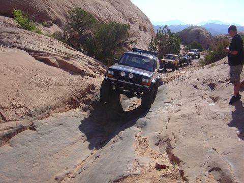 1986 Ford Bronco II - Off-road vehicles traverse a challenging rocky path under a clear sky.