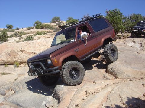 1986 Ford Bronco II - This 1986 Ford Bronco II navigates a challenging rocky trail under a clear blue sky.