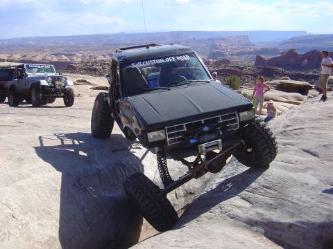 1986 Ford Bronco II - Modified 1986 Ford Bronco II navigating rocky terrain with a Jeep in the background.