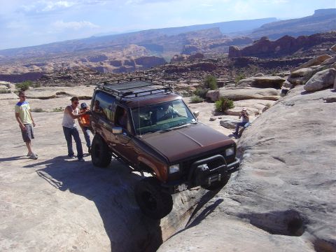 1986 Ford Bronco II - A brown Ford Bronco II navigates a narrow rocky path with people assisting.