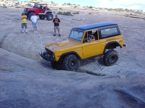 1986 Ford Bronco II - Yellow 1978 Ford Bronco navigating rocky terrain, with a red Jeep visible behind.
