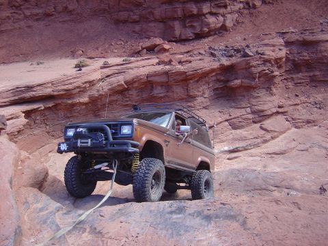 1986 Ford Bronco II - This modified 1986 Ford Bronco II navigates a steep, rocky trail in a desert landscape.