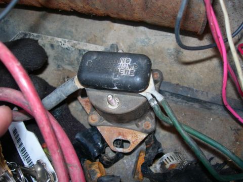 1984 Ford Bronco - Close-up of an ignition coil with a warning label indicating where to jump-start.