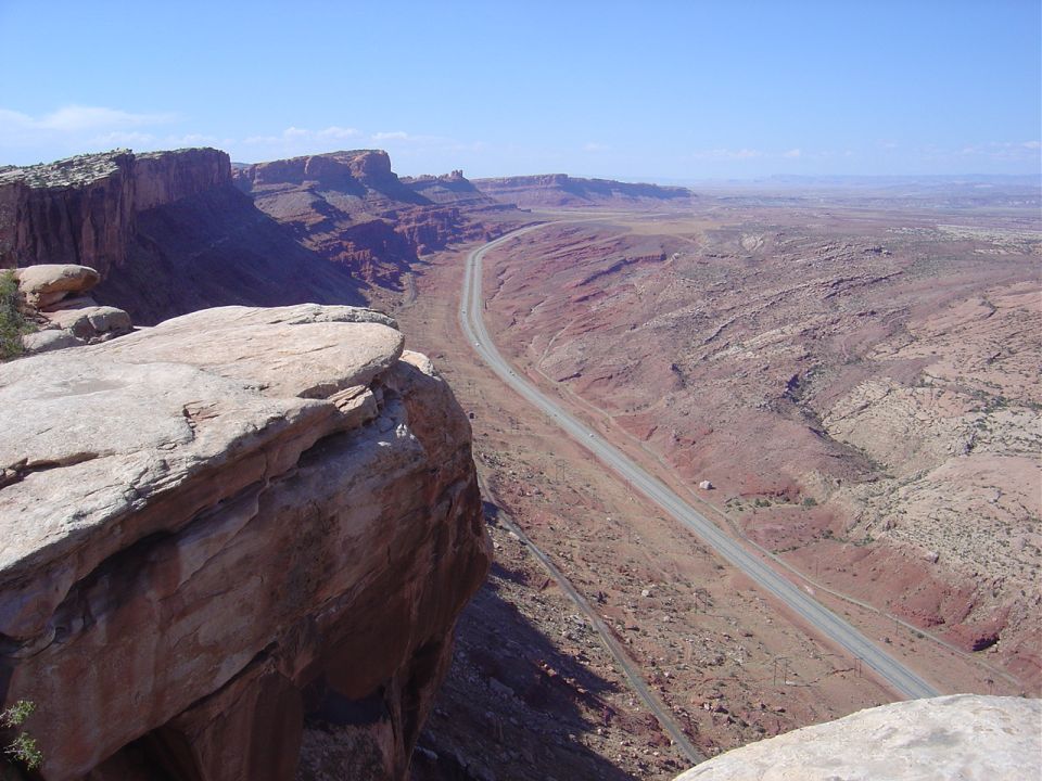 Desert canyon with a road winding through it, seen from a high cliff
