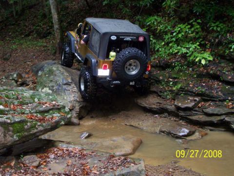 1992 Jeep Cherokee - A Jeep Wrangler navigates a challenging off-road course with water and rocks.
