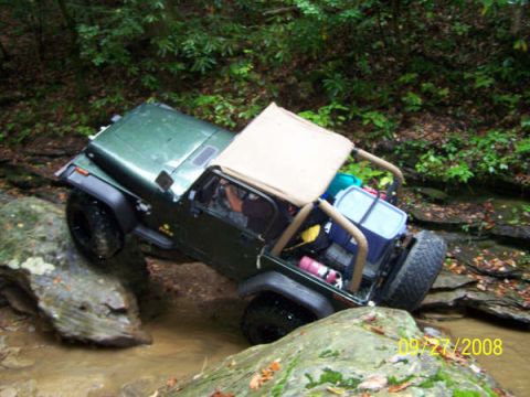 1992 Jeep Cherokee - Jeep Wrangler TJ navigating a rocky stream bed during an off-road excursion.
