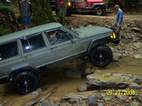 1992 Jeep Cherokee - Off-roading in a 1992 Jeep Cherokee on a wooded trail with water crossing.