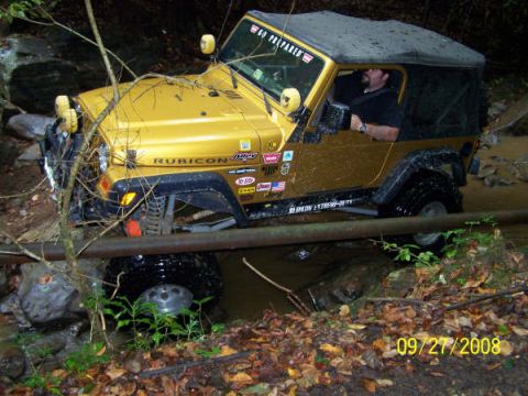 1992 Jeep Cherokee - Off-road Jeep Wrangler navigating a stream on a trail, driver at the wheel.