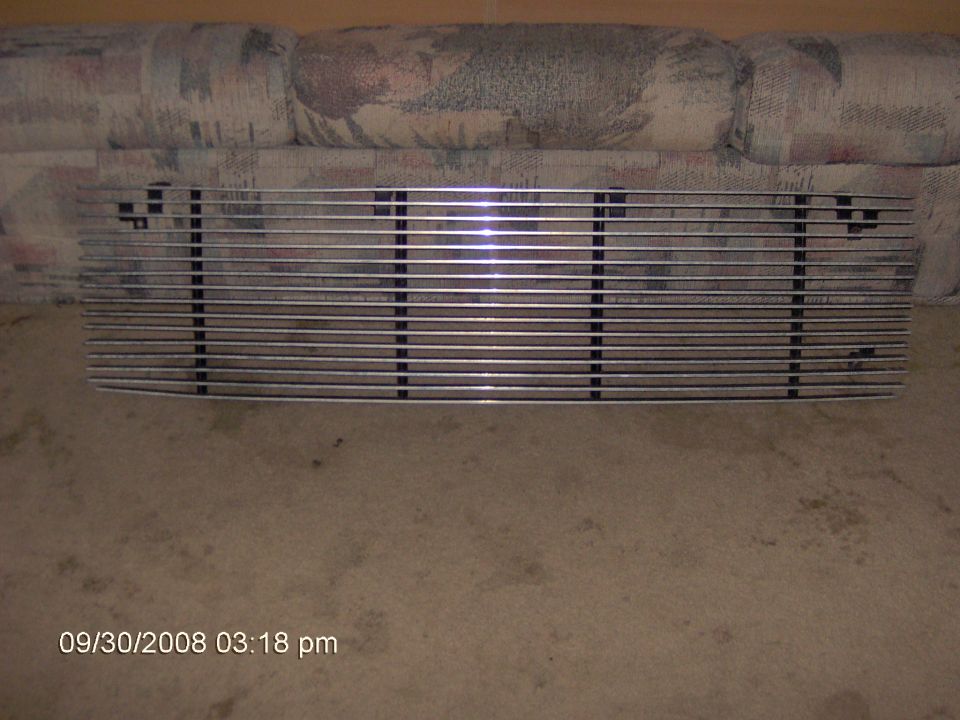 Chrome billet-style horizontal-bar grille leaning against a couch