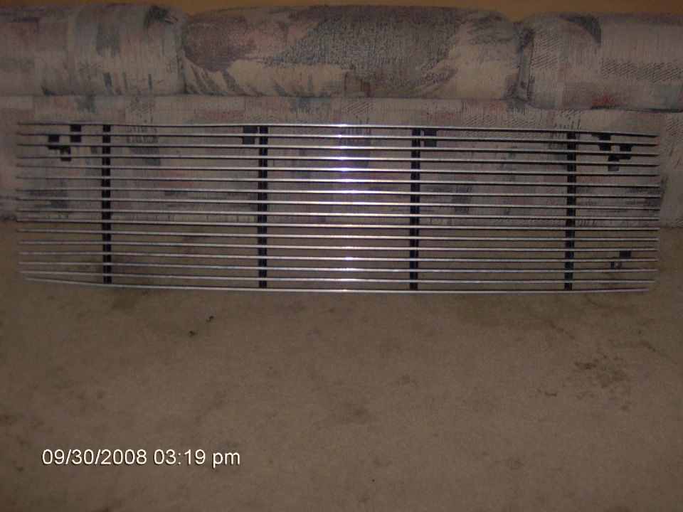 Chrome horizontal-bar billet grille propped against a patterned couch