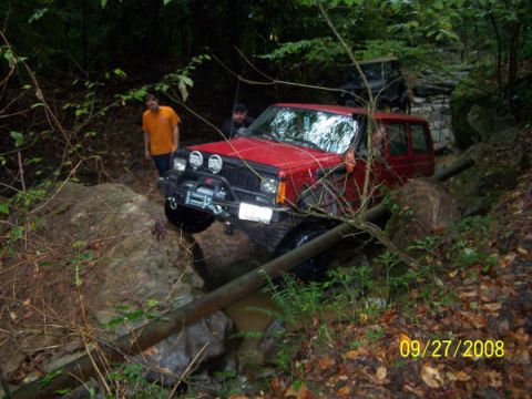 1992 Jeep Cherokee - Off-roading adventure in a 1992 Jeep Cherokee, navigating a challenging wooded terrain.