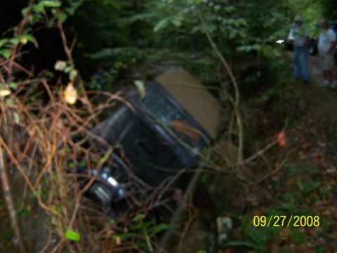 1992 Jeep Cherokee - A Jeep Cherokee lies off the road, tangled in vegetation after an apparent crash.