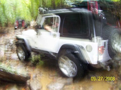 1992 Jeep Cherokee - Two Jeep Wranglers navigate a challenging muddy trail during an off-road excursion.