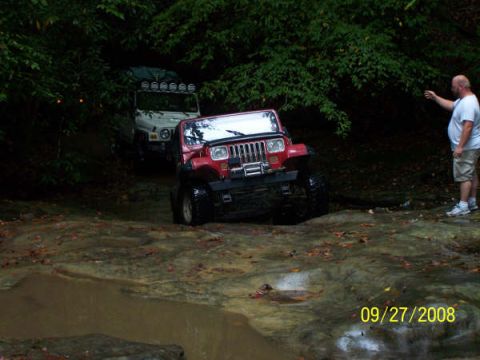 1992 Jeep Cherokee - Two Jeep SUVs navigate a muddy trail with a man observing the scene.