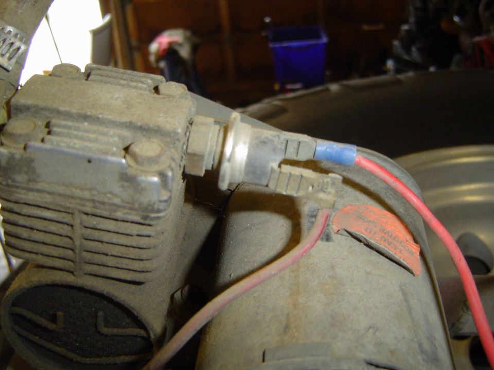 Close-up of a dusty engine component with red and blue wires connected