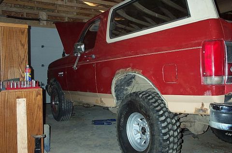 1987 Ford Bronco - Red 1987 Ford Bronco with tan trim parked in a garage, hood open, undergoing work.