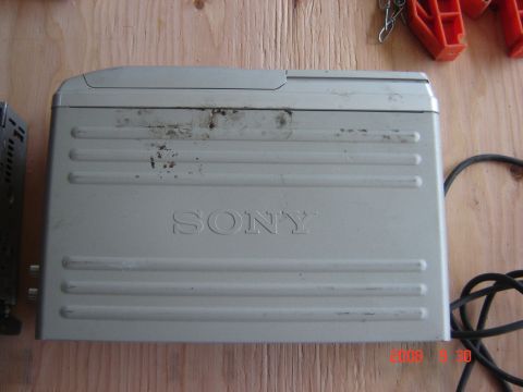 1993 Ford Bronco - A silver Sony CD changer is shown on a wooden surface, with a black cable attached.