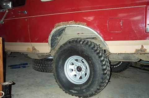 1987 Ford Bronco - The vehicle shows significant rust damage on its body, particularly around the rear wheel well and lower trim.